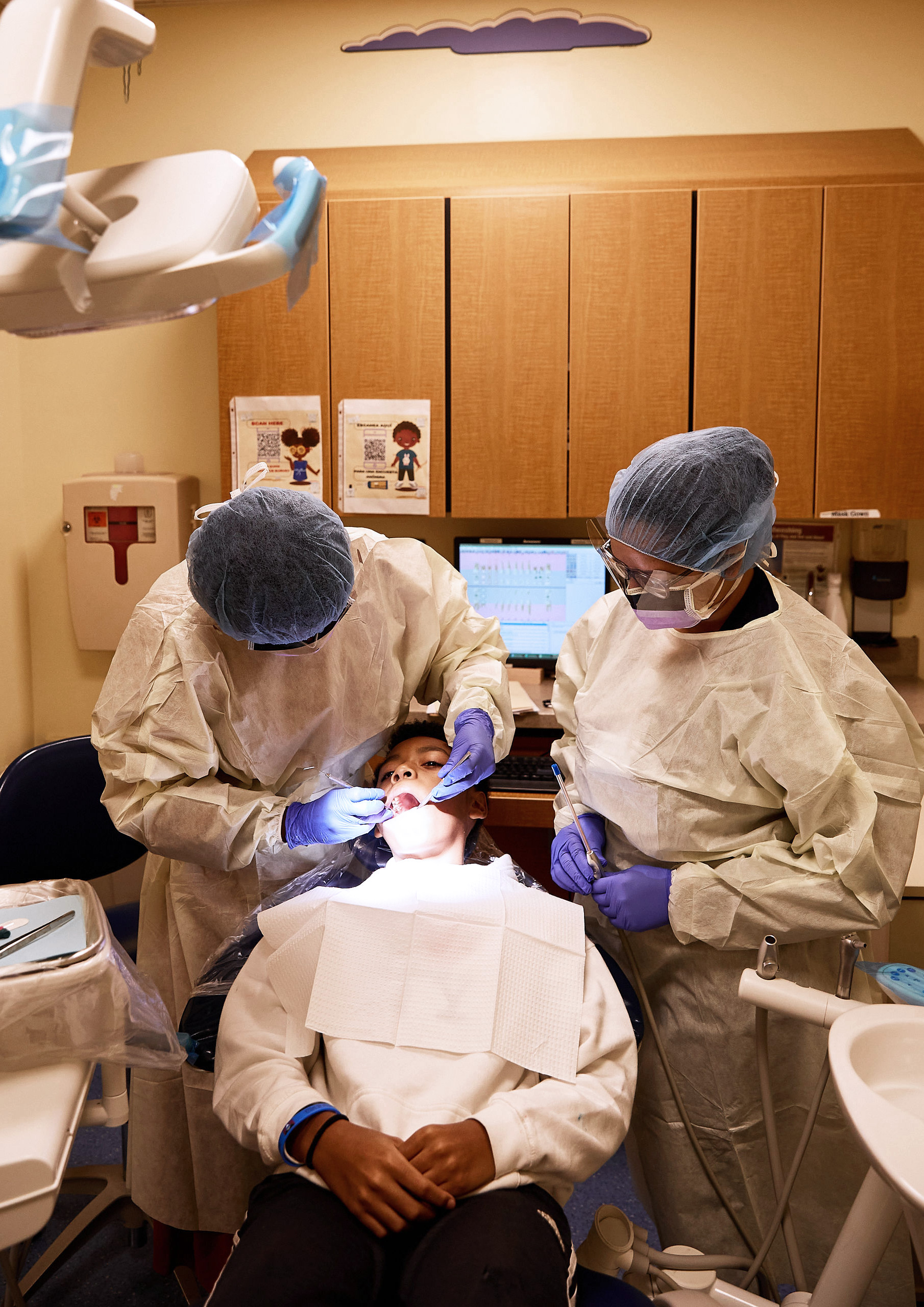 Dr. Ann Layvey-Tardalo, Pediatric Program Director (left), examining patient, with Eliana Reyes, Dental Assistant.