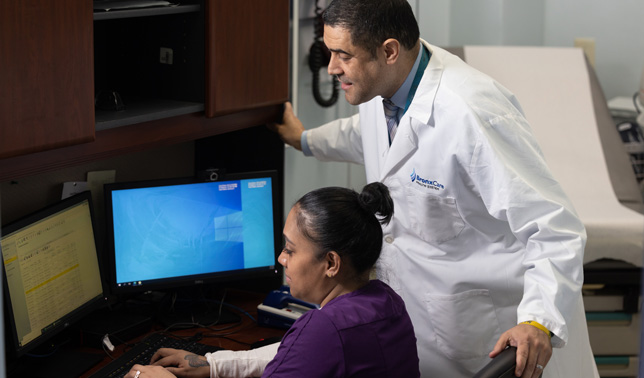 Dr. Jose Tiburcio, Vice Chairman, Family Medicine/Director, Residency Program, reviewing patient information with Alicia Mosquera, Medical Assistant.