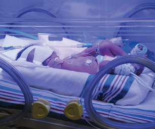 Infant resting in incubator.