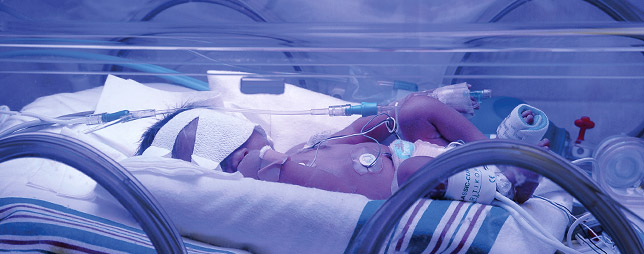 Infant resting in incubator.