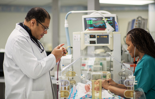 El Dr. Yves Verna, especialista en neonatología, y Venjay Johnson, enfermero registrado y enfermero practicante de obstetricia/ginecología, supervisando el progreso de un recién nacido.